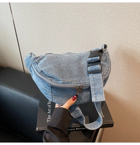 Macro detail of blue denim crossbody bag featuring metal double zippers and wide strap