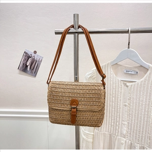 Détail du sac bandoulière en paille tressée avec lanière en cuir marron et boucle en métal