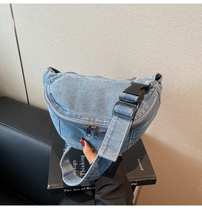 Close-up of a blue denim waist bag with double zippers and black plastic buckle detail