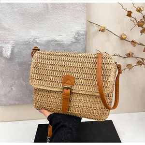 Détail de la texture d'un sac bandoulière en paille tressée avec boucle en cuir marron