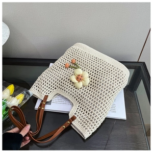 Dettaglio della borsa tote crema tessuta a mano con ciondolo floreale e manici in pelle