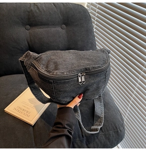 Detail of dark denim crossbody bag featuring textured fabric and dual metal zippers