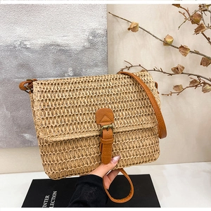 Détail du sac en paille tressée avec bandoulière en cuir et boucle métallique décorative