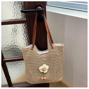 Dettaglio della borsa tote in rete intrecciata con fiore bianco 3D e tracolla in pelle