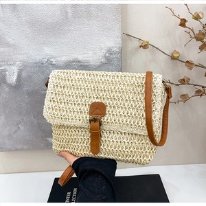 Détail d'un sac bandoulière en paille tressée avec lanière en cuir brun et rabat élégant