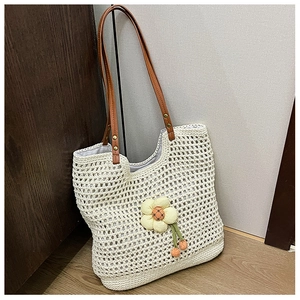 Dettaglio della borsa tote intrecciata bianca con ciondolo a fiore giallo e manici marroni