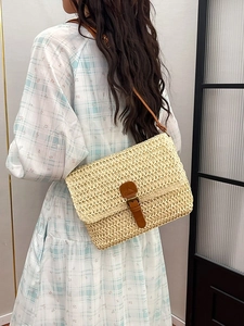 Sac bandoulière en paille beige vintage avec bandoulière en cuir marron porté par un modèle