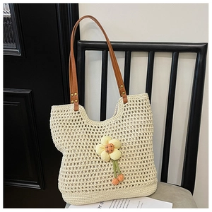 Dettaglio borsa tote intrecciata beige con manici in finta pelle marrone e fiori applicati