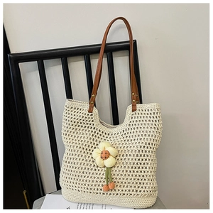 Dettaglio della borsa tote in maglia con ciondolo a fiore beige e manici in pelle
