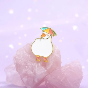Cute white duck enamel pin with rainbow umbrella hat and orange boots on pink crystal base