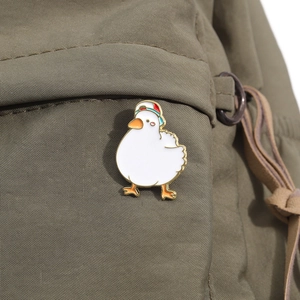 Detail of cute enamel white duck pin with sports cap attached to a canvas bag