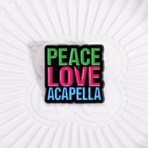 Close-up of Peace Love Acapella colorful enamel letter brooch on a textured background