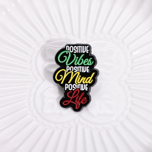 Close-up of enamel inspirational quote brooch on a minimalist white ceramic plate