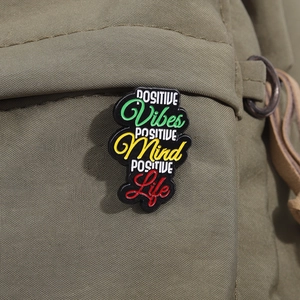 Macro view of inspirational quote enamel pin on a green canvas bag background