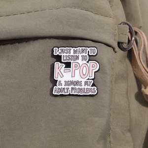 Close-up of a K-Pop themed enamel brooch pinned on a green canvas bag for decoration