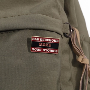 Macro shot of rectangular enamel pin with quote Bad Decisions Make Good Stories