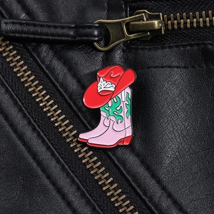 Broche émaillée bottes de cowboy roses et chapeau rouge sur une veste en cuir