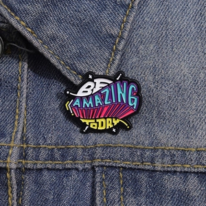 Close-up of Be Amazing Today enamel pin with colorful letters on a blue denim jacket