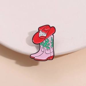 Épingle émaillée bottes de cowboy roses et chapeau rouge sur présentoir rond blanc