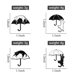 Macro shot of enamel pins showing black and white cats playing on umbrellas with dimensions
