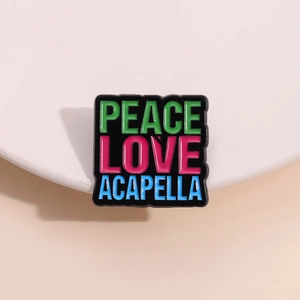 Square black enamel pin featuring colorful Peace Love Acapella text on a white pedestal