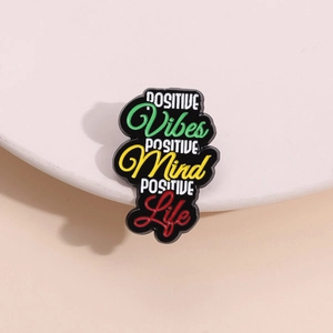 Macro shot of colorful enamel lapel pin with positive life quotes on white display