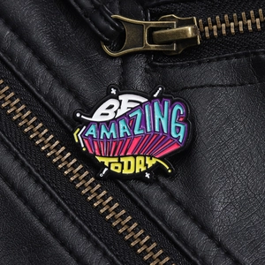 Detail of multi-color Be Amazing Today enamel brooch pinned on a black leather jacket