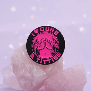 Creative round enamel pin featuring I Love Guns and Titties typography on purple stones