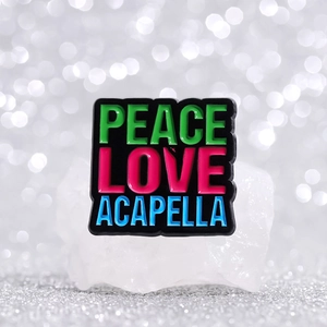 Enamel brooch with colorful Peace Love Acapella lettering on a black metal base
