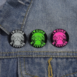 Three colorful enamel pins pinned to denim jacket featuring guns and text graphics