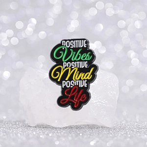 Positive Vibes Mind Life inspirational enamel pin on white stone with bokeh background