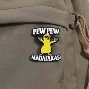 Detail of a funny cartoon yellow duck enamel pin with sunglasses on a green canvas bag