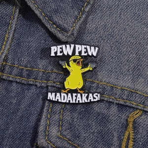Cartoon yellow duck enamel pin with sunglasses and pistols on denim background