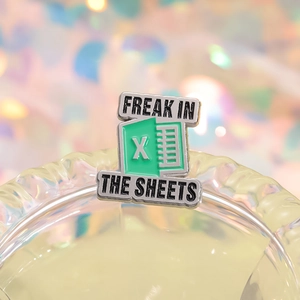 Excel spreadsheet enamel pin with Freak In The Sheets quote on glassware background