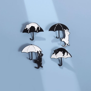Minimalist black and white cat enamel pins featuring playful designs on umbrellas