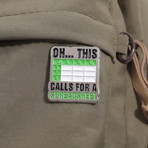 Green and white Excel spreadsheet enamel pin with humorous office quote on canvas