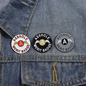 Nahaufnahme von Asshole Merit Badge Emaille-Anstecknadeln an einer Jeansjacke