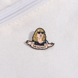 Detail of enamel pin featuring a blonde woman with sunglasses and a pink quote ribbon