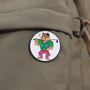 Close-up of bulldog golfer enamel pin attached to a green canvas bag strap