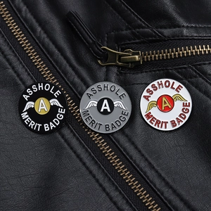 Detailansicht von drei bunten Asshole Merit Badge Emaille-Pins auf einer Lederjacke