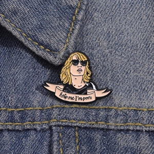 Macro shot of an enamel pin on denim showing a movie character and help me I'm poor text