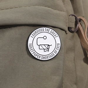 Detail of toilet paper shortage commemorative enamel pin on a green canvas fabric
