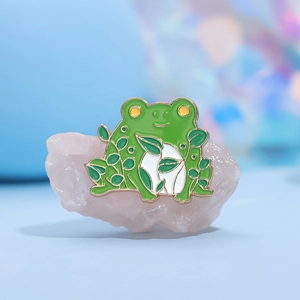Cartoon green frog enamel pin brooch with leaf pattern on light pink crystal base