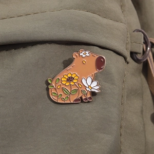 Détail d'un pin's émaillé capybara avec tournesol sur un sac en toile vert olive