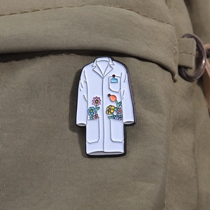 Detailansicht einer weißen Emaille-Brosche im Laborkittel-Design mit Blumenmuster