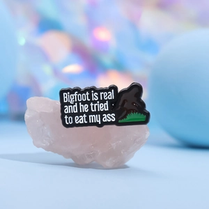 Funny Bigfoot is Real enamel pin with black silhouette design on pink crystal