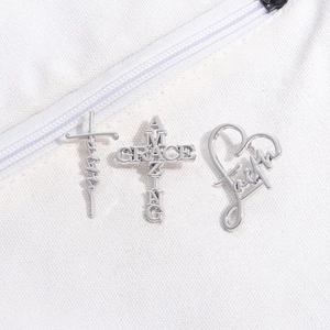 Detailed silver hollow metal pins featuring Faith and Amazing Grace on white fabric