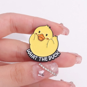 Spilla smaltata papera gialla con slogan What The Duck su sfondo rosa delicato
