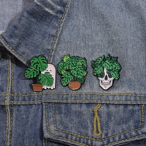 Green plant cartoon enamel pins with ghost and cactus design on blue denim jacket