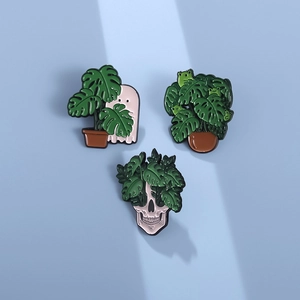 Three-piece enamel pin set featuring monstera plants with ghost, frog, and skull elements